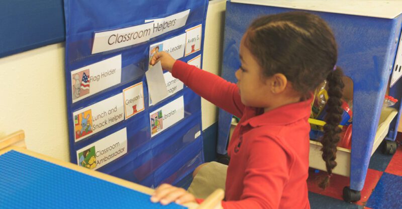 Young girl organizes the classroom job chart