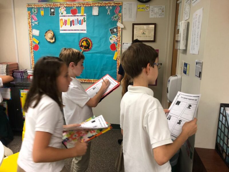 Children holding sheets of paper on a classroom scavenger hunt