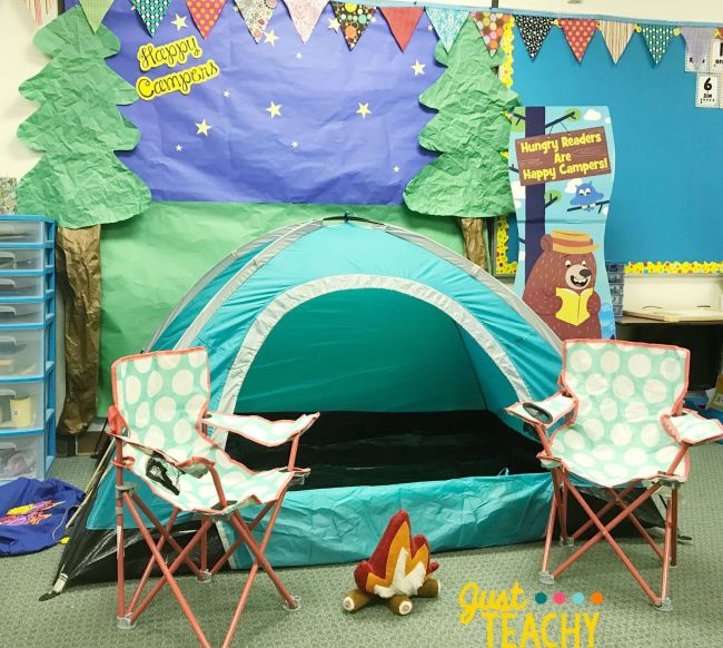 Small camping tent in a classroom with folding chairs and a paper fire creating a camping theme