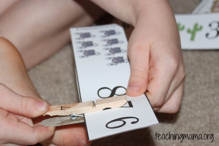 A child clips a clothespin onto a number line
