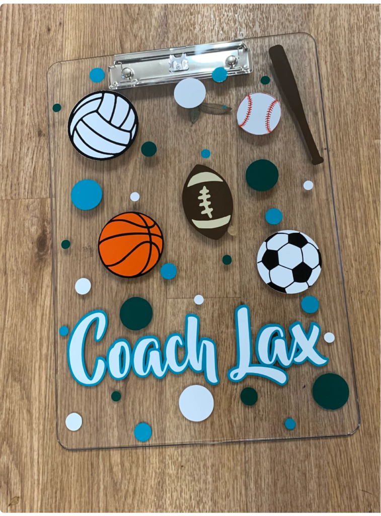 Clear clipboard that is painted with the name Coach Lax and sports balls.