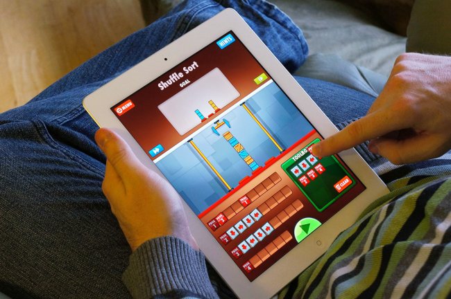 Child holding an iPad and playing Cargo-Bot, a coding game