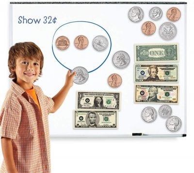 Student pointing at a board with coins and dollar bills on it -- 1st grade classroom supplies