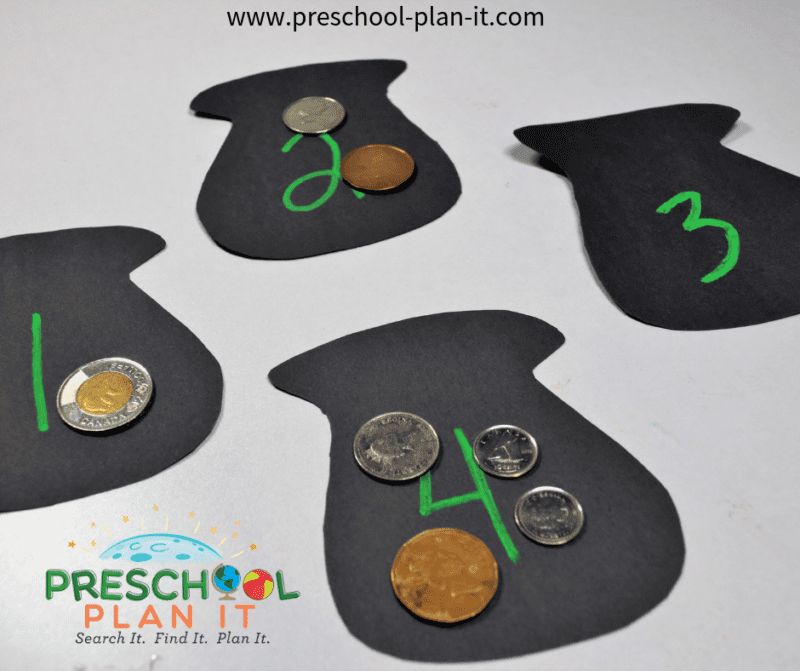 Black pots are cut out with numbers on them reading, 1, 2, 3, and 4. Plastic coins are placed on each shamrock in the amount matching the number (St. Patrick's Day crafts for kids)