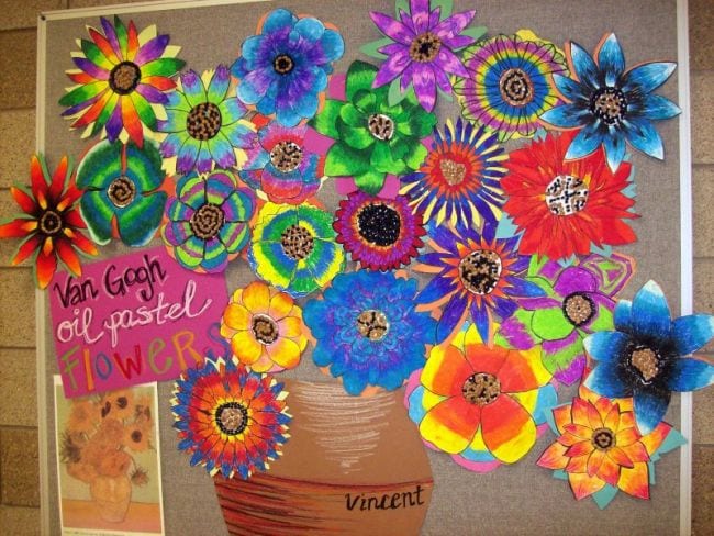 A collaborative art project featuring a painted pot filled with colorful blooms, each one made by a different student