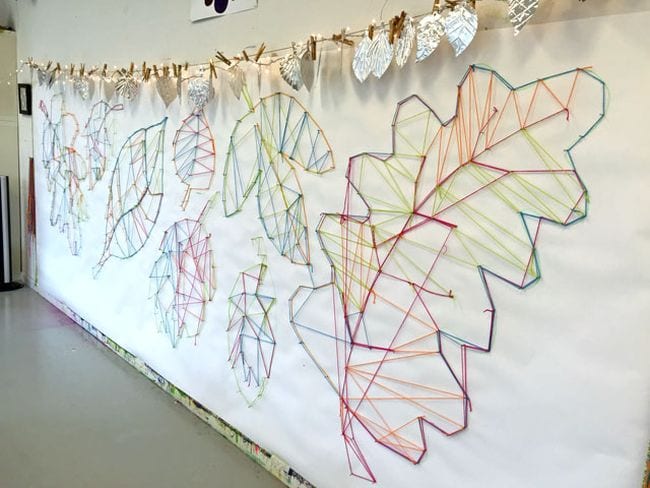 Large leaf outlines made from string hung between nails on the wall