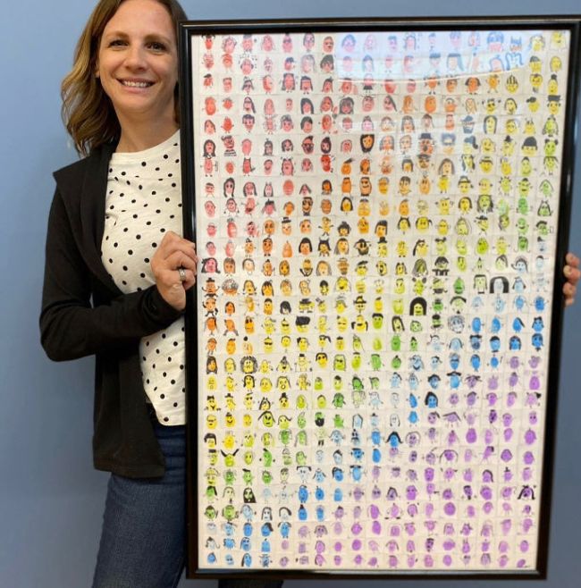Teacher holding a colorful collage of tiny thumbprint faces (Collaborative Art Projects)
