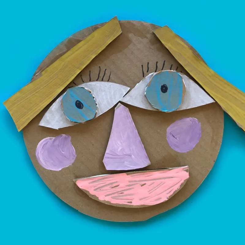 A face is constructed from cardboard pieces that have been painted.