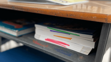 Inside of a student's desk with color-coded workbooks