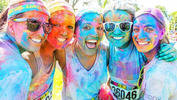 Five girls with multi-colored faces gather after a color run
