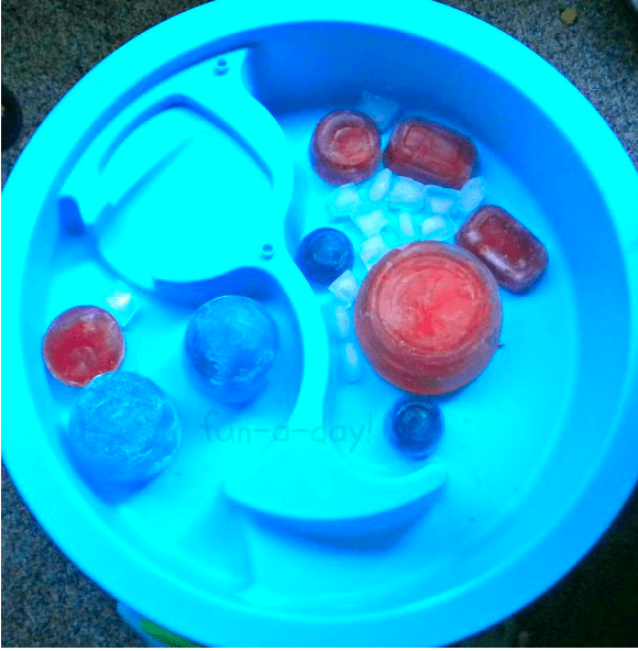Blocks of colored ice in a water table made by freezing colored water in containers and balloons