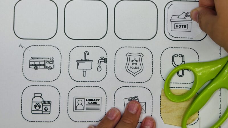 Community Helper Worksheet Close up of student hands doing a community helper cut and paste worksheet.