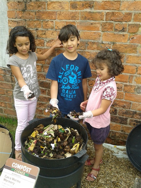 three students putting food scraps in a compost bin
