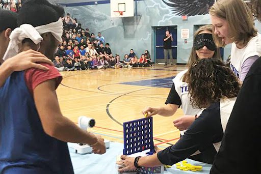 Students playing Connect 4 while being blindfolded in this example of pep rally activities