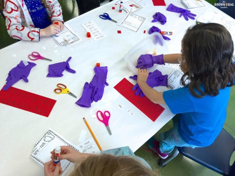 students with purple plastic gloves on cutting apart words and taping them back together with bandaids as an example of grammar games