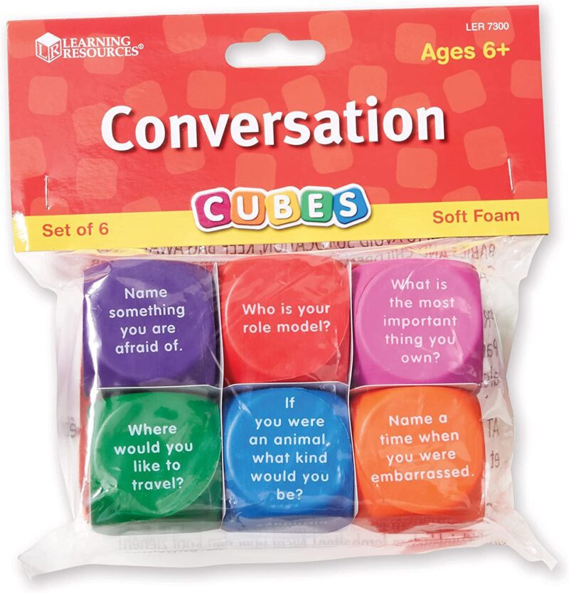 A bag has dice in it that have different conversation starters on them. Each dice is a different bright color.