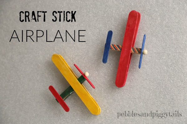 Two small airplanes are shown made from a clothespin, different size popsicle sticks, and a wooden bead. They are painted.