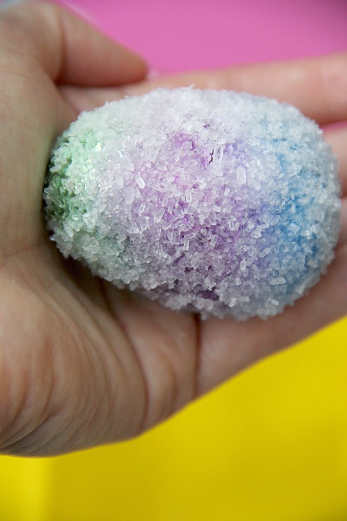 hand holding an egg colored and covered in borax for a plastic egg activity 