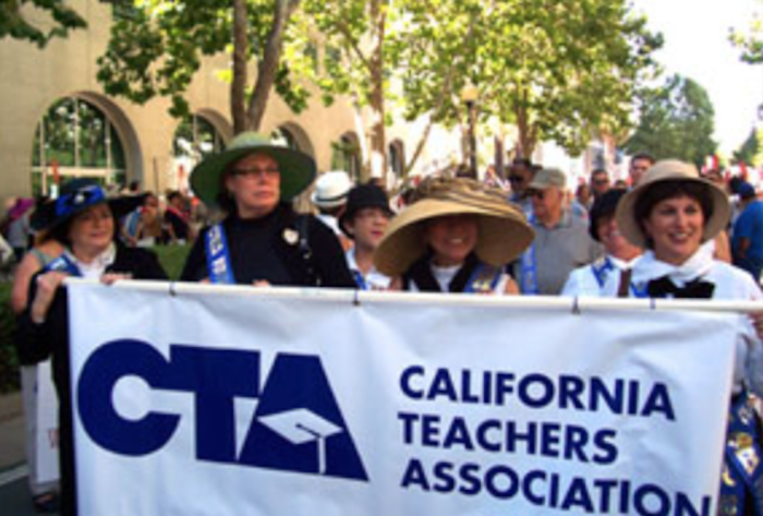 teachers carrying a sign that says california teachers association (teachers union)