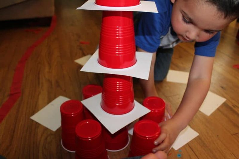 Preschooler making a stack of red plastic cups and index cards
