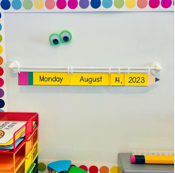 A magnetic curtain rod is on a board and the date is written on laminated pencils hanging from curtain rings.