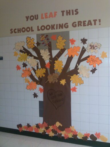 October bulletin board ideas include this tree that reads "you leaf this school looking great." The bark is made of brown construction paper with different Autumn colored leaves that have notes of thanks on them for custodians.