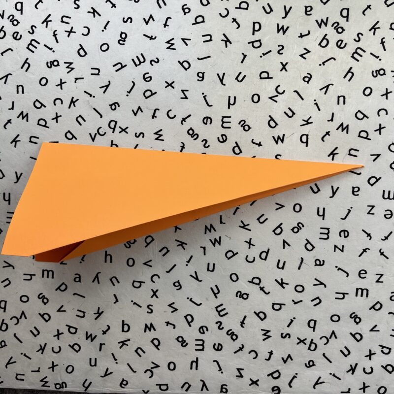 Orange folded paper- how to make paper airplanes
