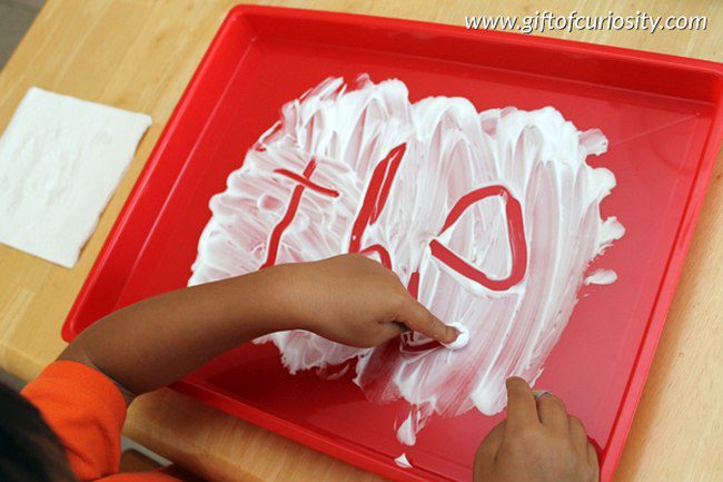 Student writing letters in shaving cream spread on a tray