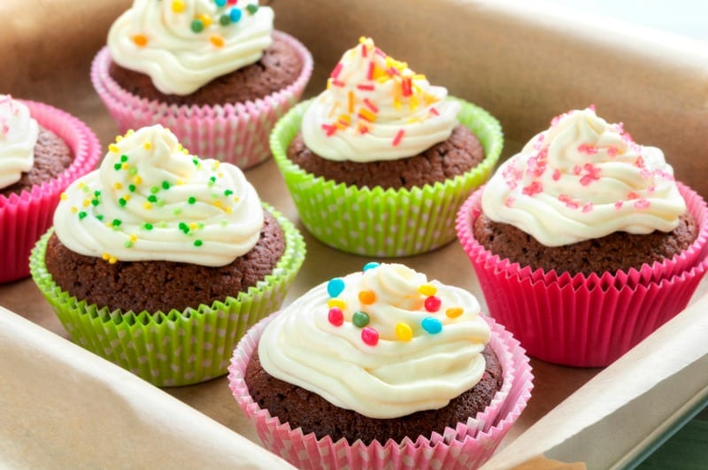 Fancy chocolate cupcakes with vanilla cream and colorful toppings and decoration