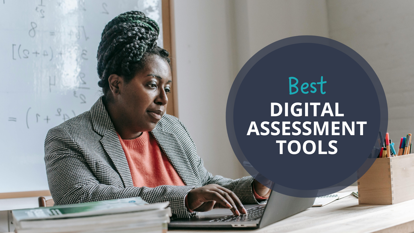 Teacher sitting at a desk looking at a laptop. Text reads Best Digital Assessment Tools.