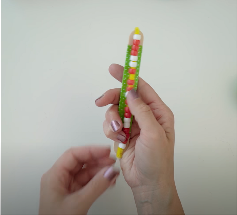 Hand holding a DIY fidget stick made of beads.