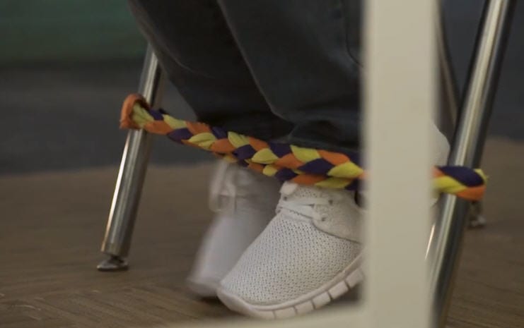Student kicking at a chair band DIY fidget made from braided strips of old t-shirts