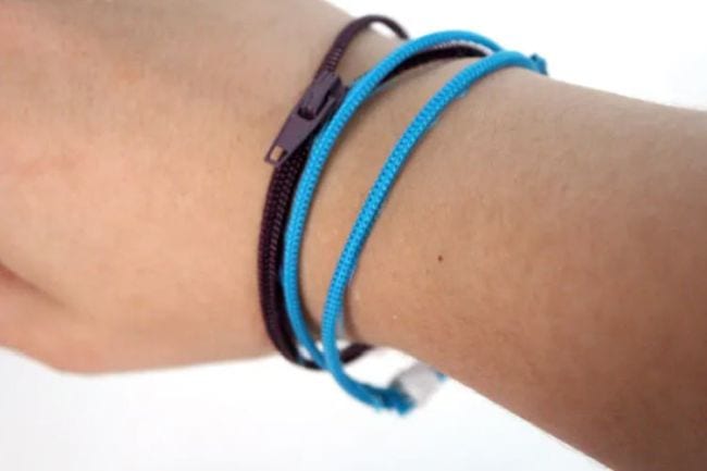 Student wearing blue and black bracelets made of zippers