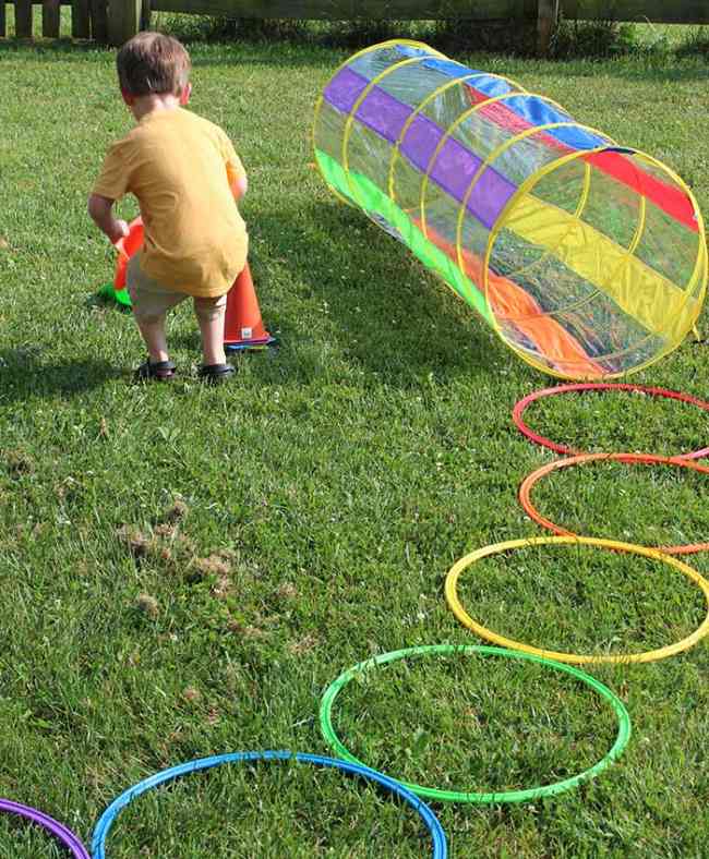 Child setting up colorful plastic cones as part of a rainbow-themed obstacle course