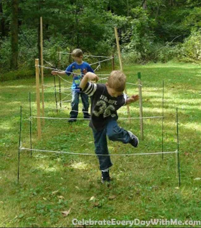 Children working their way over and under a series of ropes in an obstacle course