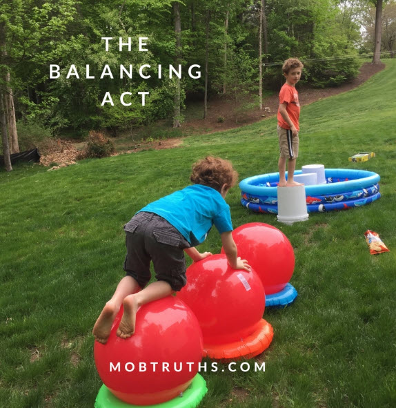 Child crawling over exercise balls balanced on inflatable rings, as part of a Wipeout themed obstacle course