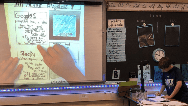 student uses a document camera to show work to the class
