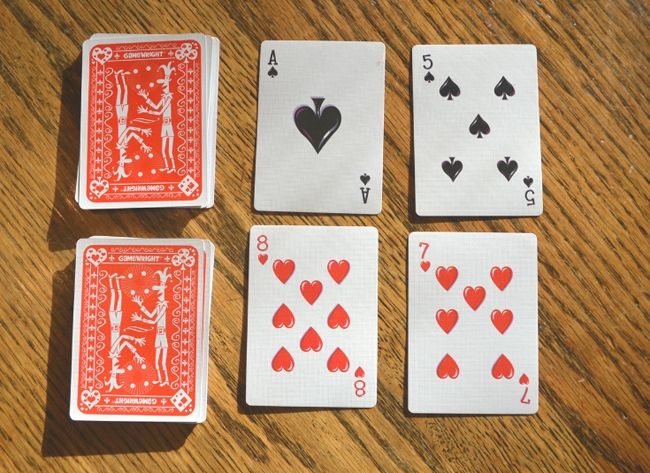 Two decks of playing cards with four cards face up next to them as an example of dollar store hacks for the classroom 