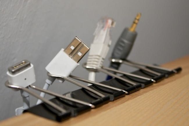 Binder clips holding charging cables to the edge of a table