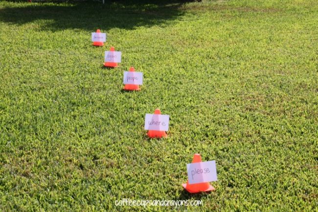 Series of small orange cones with words taped to them laid out on grass