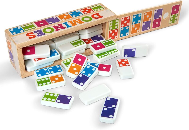 A colorful box says Dominoes and has dominoes spilling out of it.