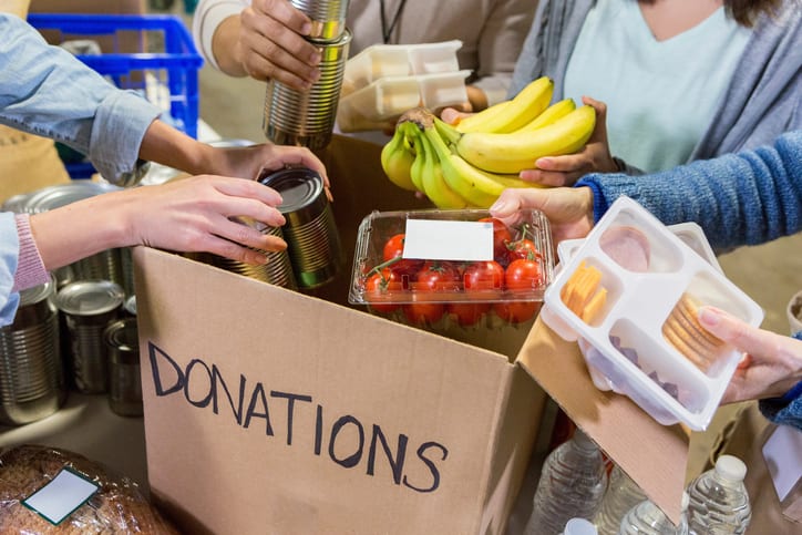 People putting food items into a donation box