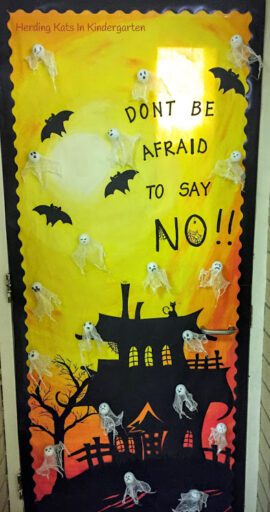 A door is decorated with a yellow background, a haunted house, skeletons, and bats. Text reads "Don't be Afraid to Say NO!!"