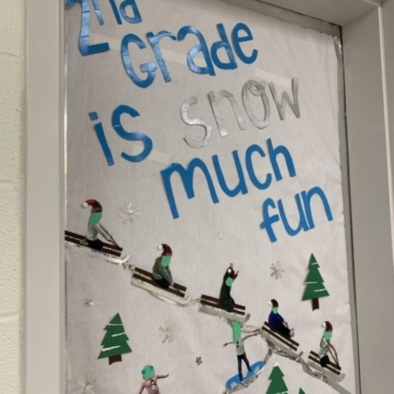 A classroom door is decorated with sledders going down a snow covered hill. Text reads 2nd grade is snow much fun. 