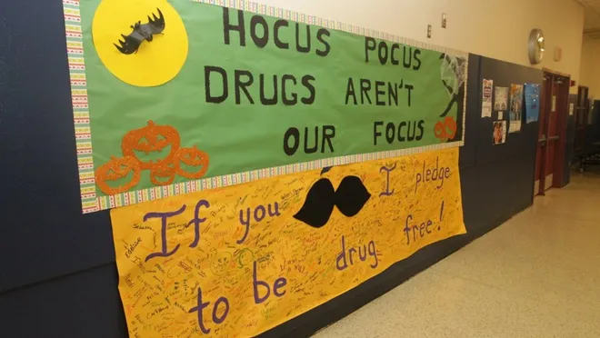 Fall bulletin boards can be in hallways like this one. The Top is green with writing that says Hocus Pocus Drugs Aren't Our Focus. Halloween decor surrounds it. 