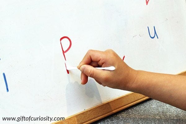 Student using a cotton swab to erase a letter drawn on a whiteboard
