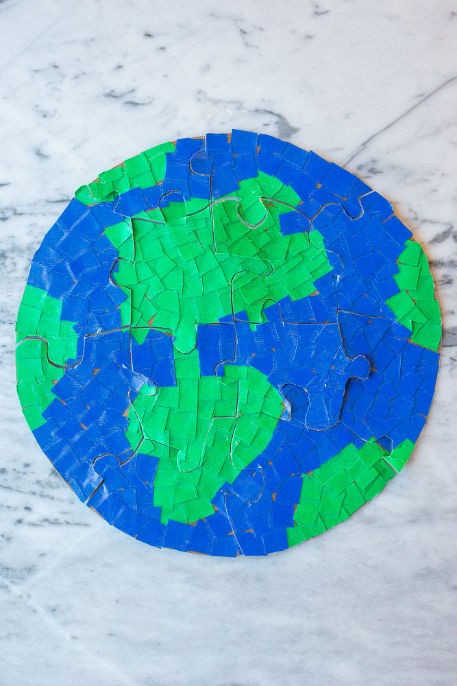 A circular puzzle in the shape of planet Earth made from blue and green puzzle pieces