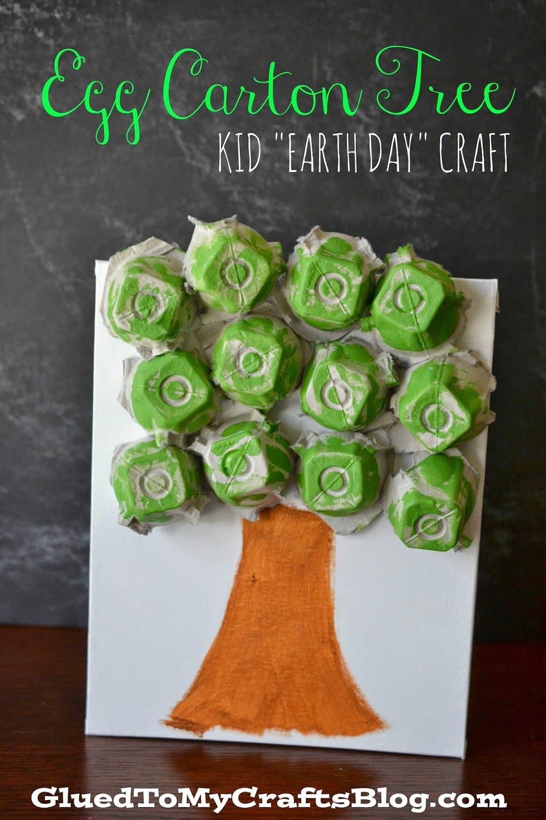 A tree trunk is painted on white paper. The leaves are made from cut up, painted green egg carton pieces (earth day crafts)