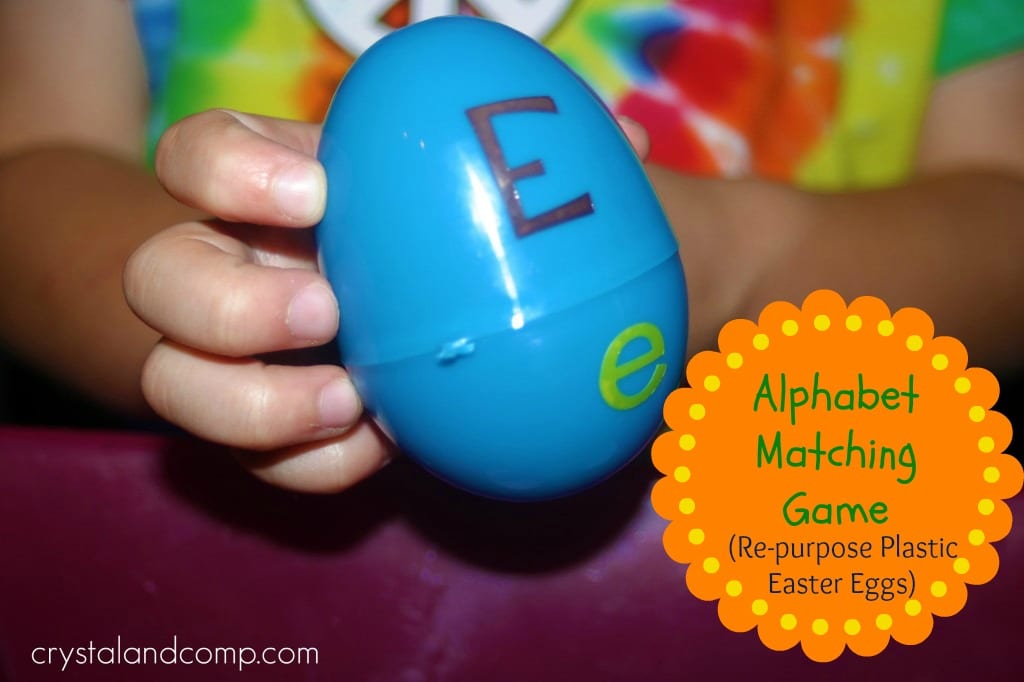 A child's hand holds a blue plastic Easter egg with a capital E written on the top half and a lowercase e on the bottom half as an example of alphabet activities