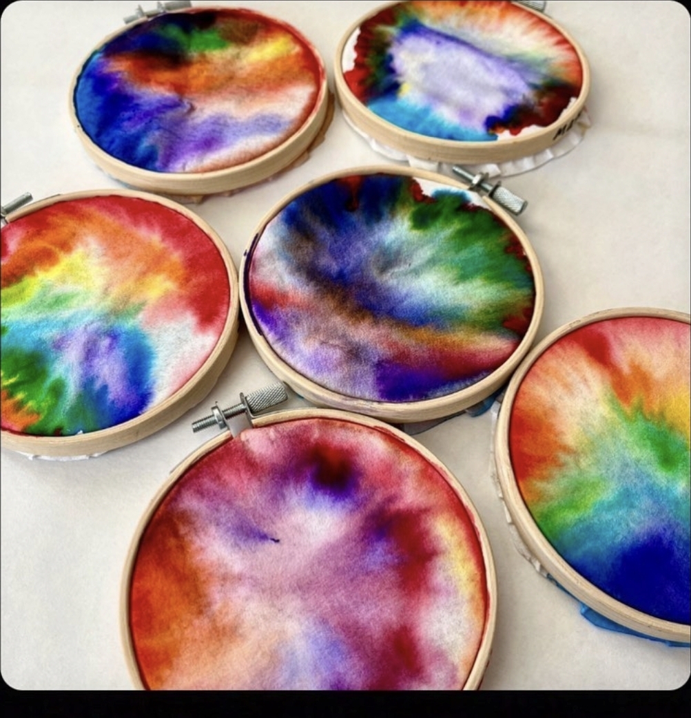 Colorful diffusing paper art designs mounted in embroidery hoops